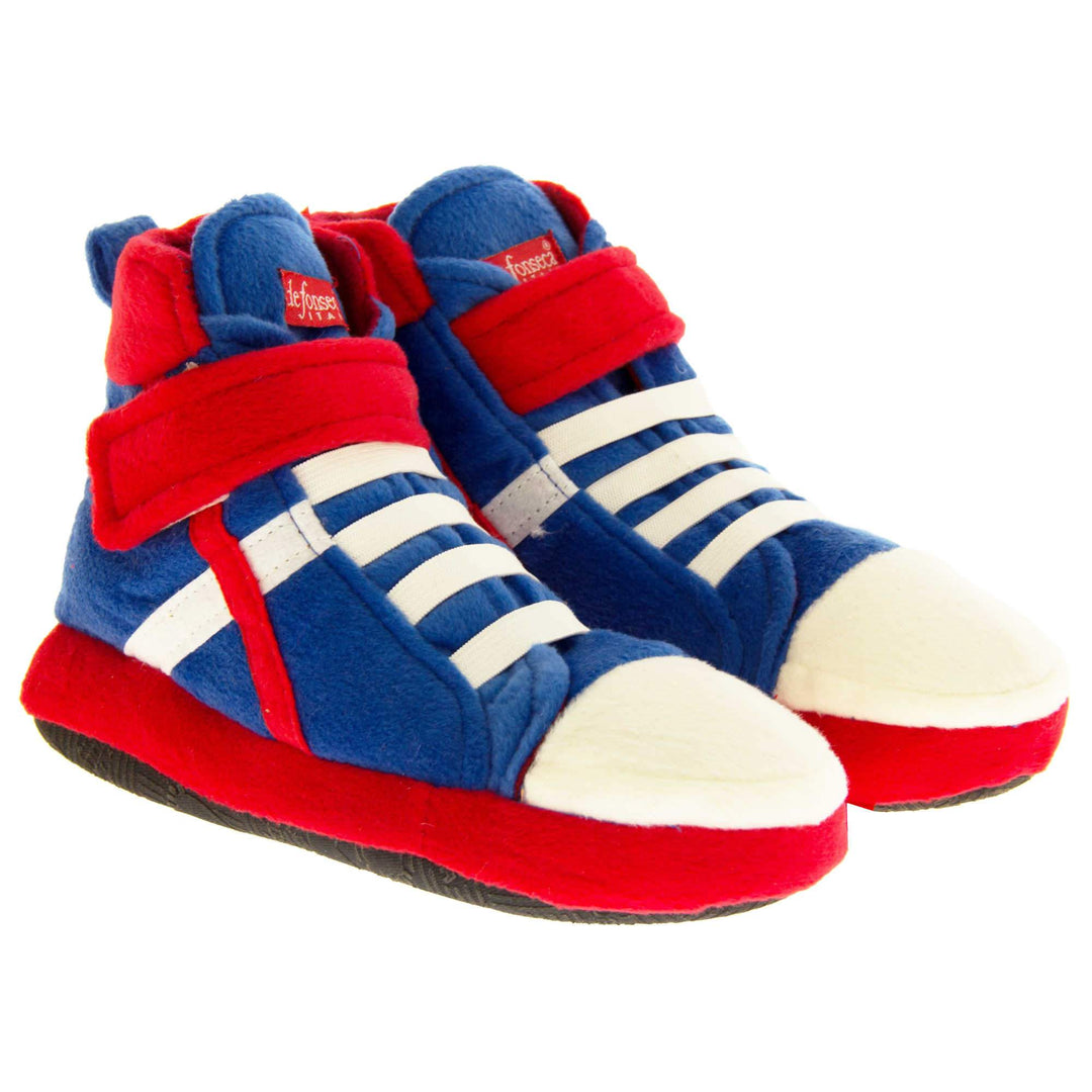 Kids High Tops Slippers. Slippers that look like high top trainers. Soft royal blue upper with white toes and elastic faux laces. White diagonal stripe on the side of the upper. Red touch fasten ankle strap and collar. Red line runs in a diagonal line to the sole. Forms a x with the white line. Thick red edging around the sole. Black sole to the bottom. Both feet together from an angle.
