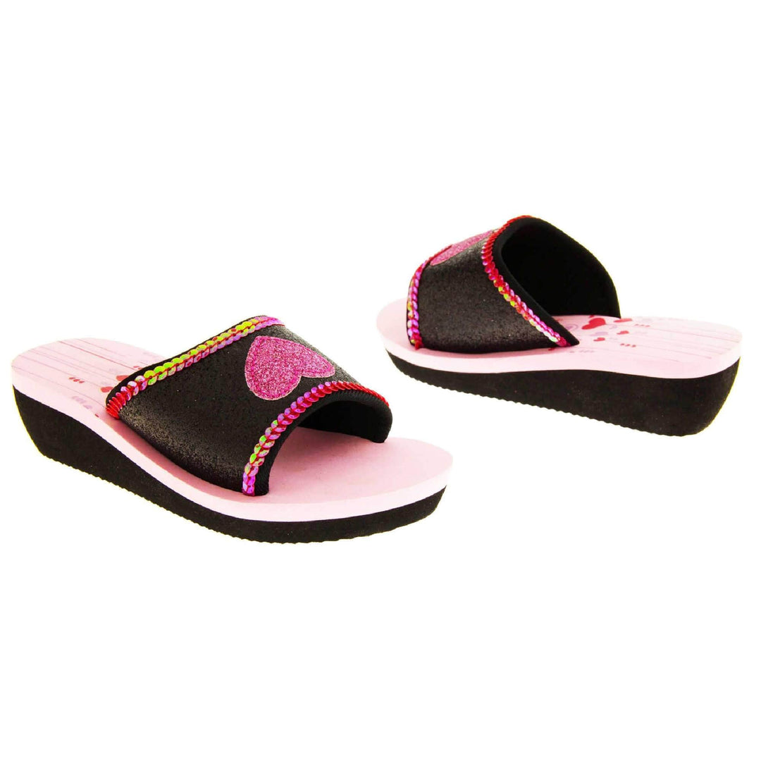 Foam wedge sandals for girls. Black bottom half of the sole with ridges for grip, baby pink top half with red and pale pink heart and line design to the heel of the insole. Black glitter full strap with bright pink glitter heart in the middle and pink sequins along the edges.  Both feet from slight angle facing top to tail.