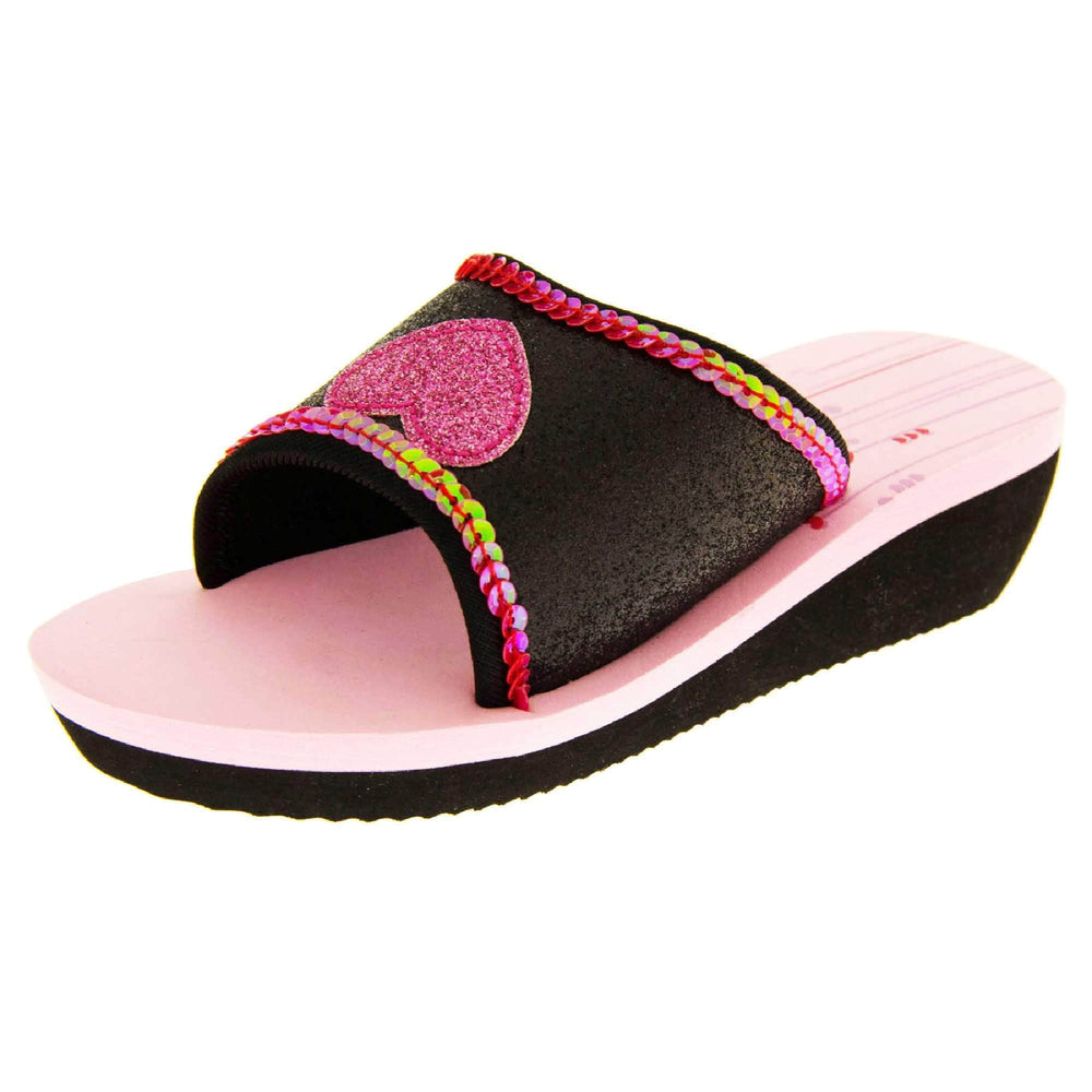 Foam wedge sandals for girls. Black bottom half of the sole with ridges for grip, baby pink top half with red and pale pink heart and line design to the heel of the insole. Black glitter full strap with bright pink glitter heart in the middle and pink sequins along the edges. Left foot at an angle.