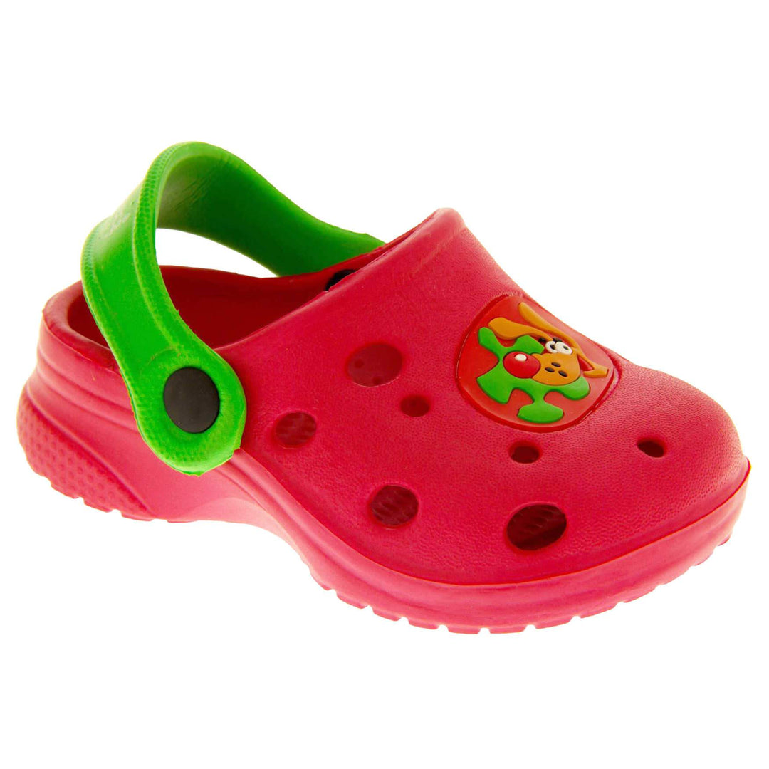 Kids Summer Clogs. Red synthetic clog style shoes. Cut out holes in the upper with a cartoon dog decal in the centre centre. Green strap that goes along the back of your heel. The strap can be moved along the top of the shoe instead to make the shoe a mule. Right foot at an angle.