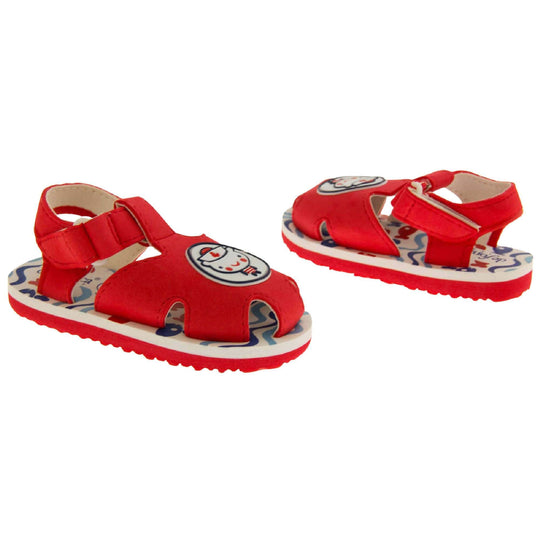 Boys Sandals. Fisherman style sandals with red upper and touch fasten ankle strap. The red upper has a white circle in the centre with a bear dressed as a sailor inside it. The inside of the upper and straps is white, as is the top half of the sole with the foot bed, which has a blue wave pattern on it. The bottom half of the sole is red and has a bumpy grip to the bottom of it. Both shoes at a slight angle facing top to tail.