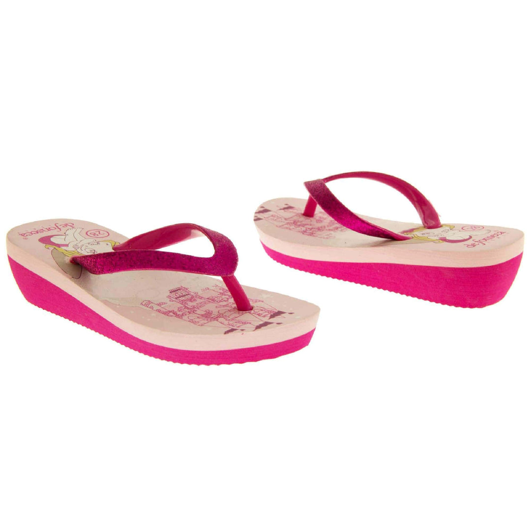 Foam wedge sandals for girls. Fuchsia bottom half of the sole with ridges for grip, baby pink top half with bright pink fantasy design to the insole. Fuchsia strap with toe post covered on top with bright pink glitter.  Both feet from slight angle facing top to tail.