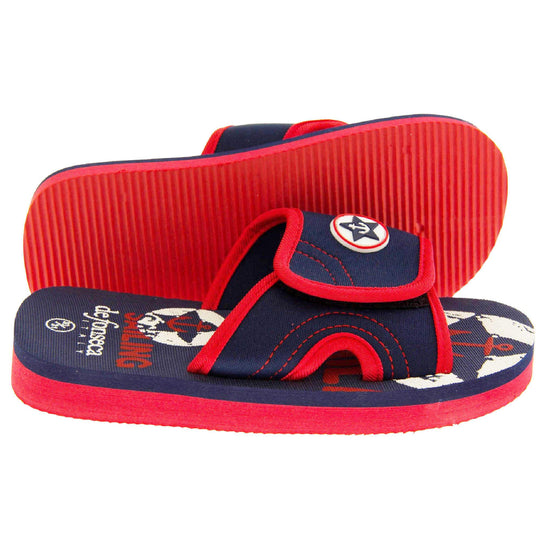Kids sliders. Slip on slider style sandals. Navy blue touch fasten strap with red around the edge and a white synthetic circle in the centre of the strap with navy anchor in the middle. The foam sole is two toned. The top half is navy, the bottom half is red. Both feet from side profile with left foot on its side to show the sole.