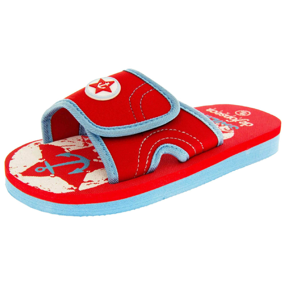 Kids slip on sandals. Slip on slider style sandals. Red touch fasten strap with light blue around the edge and a white synthetic circle in the centre of the strap with red anchor in the middle. The foam sole is two toned. The top half is red, the bottom half is pale blue. Left foot at an angle.