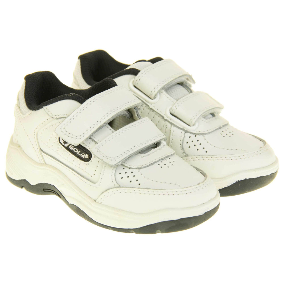Kids trainers. White leather Gola trainers with fabric tongue. With Gola branding and logo on the side and two touch close straps. The lining is black textile. White chunky sole with black base. Both feet together from a slight angle.