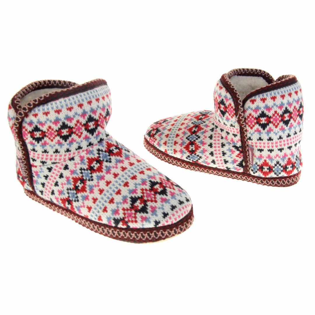 Knitted boot slippers. Womens ankle boot style slippers with a white knit upper and multi coloured pattern in a Scandinavian Aztec style. Cream plush faux fur lining. Both feet at an angle, facing top to tail.