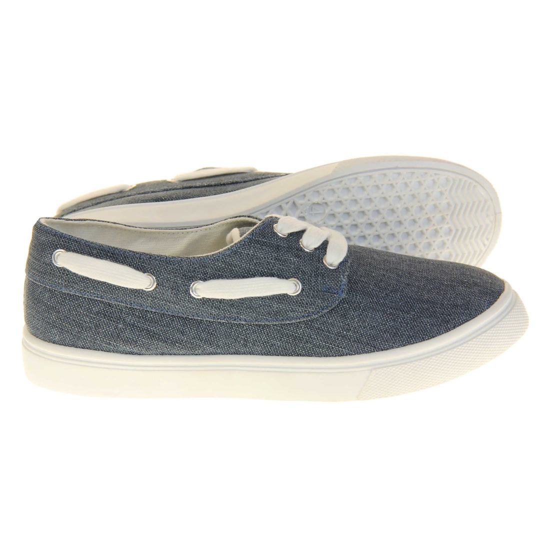 Ladies canvas slip on shoes. Sneaker style shoes with a navy blue canvas upper and white laces and white lace detailing around the outside of the collar. White outsole with slip-resistant grip to the bottom. Both feet from a side profile with the left foot on its side behind the the right foot to show the sole.