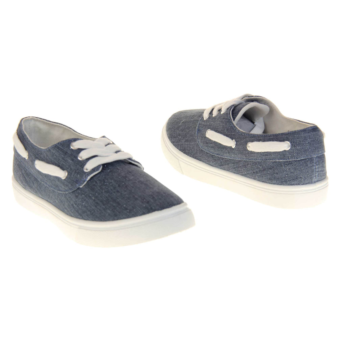 Ladies canvas slip on shoes. Sneaker style shoes with a navy blue canvas upper and white laces and white lace detailing around the outside of the collar. White outsole with slip-resistant grip to the bottom. Both feet at an angle facing top to tail.