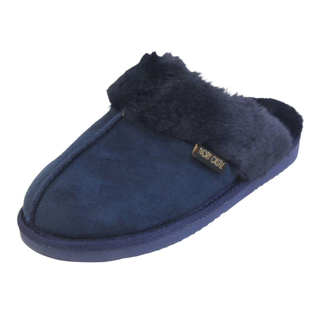 Ladies Faux Fur Mule Slippers. Slip on style slippers with Navy blue faux suede uppers. Navy faux fur lining and collar. Firm blue outsole with grip on the bottom. Left foot at an angle.