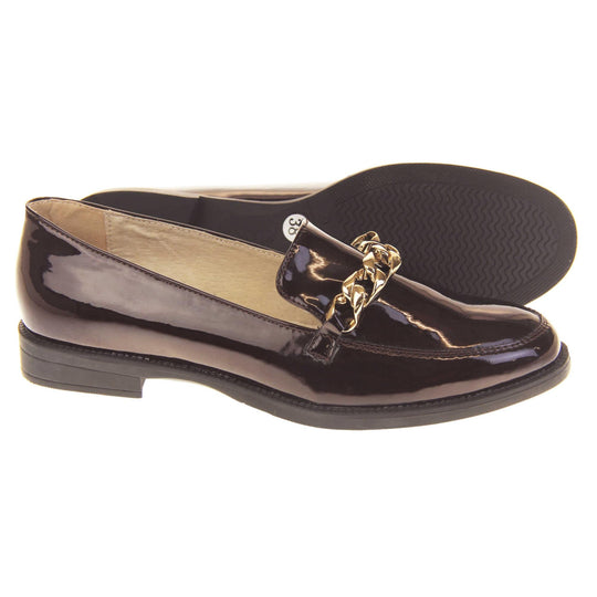 Ladies leather flat shoes. Loafer shoes in a Brogue style with a burgundy faux leather upper. Gold chain detail over the tongue. Real leather lining. Black sole with a slight heel. Both feet from a side profile with the left foot on its side behind the the right foot to show the sole.