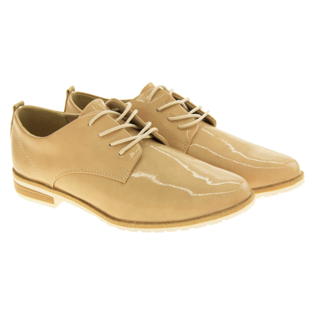 Ladies oxfords. Womens oxford style shoes with a beige patent faux leather upper. Stitching detail to the sides. Cream laces and beige lining. Brown and cream sole with a very slight heel. Both feet together at a slight angle.