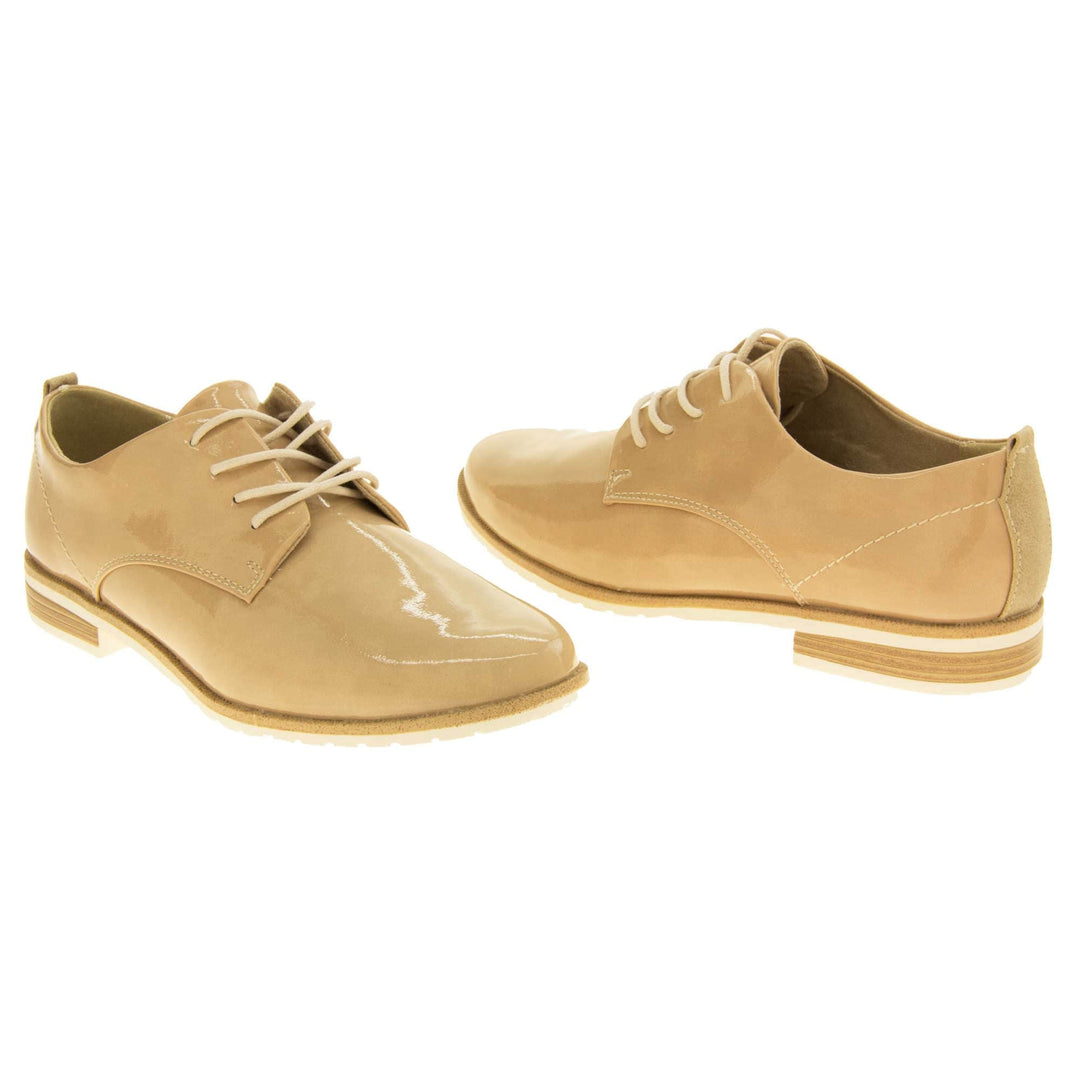 Ladies oxfords. Womens oxford style shoes with a beige patent faux leather upper. Stitching detail to the sides. Cream laces and beige lining. Brown and cream sole with a very slight heel. Both feet at an angle facing top to tail.
