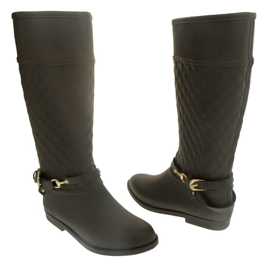 ladies wellies. Women's wellington boots in a knee length style. Black rubber upper with the leg done in a quilted effect. black rubber strap with buckle detail around the ankle. Black non slip sole. Both feet from a slight angle facing top to tail.