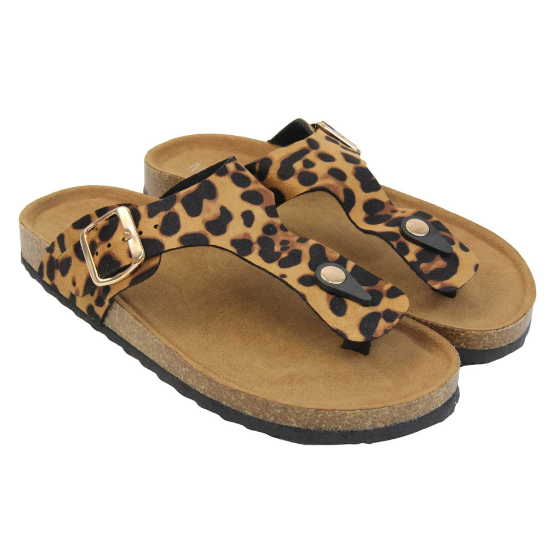 Leopard print flip flops. Leopard print faux suede strap with toe post to the front and gold buckle to the outside. Soft tan faux suede footbed with cork effect outsole and black sole. Both feet together at a slight angle.