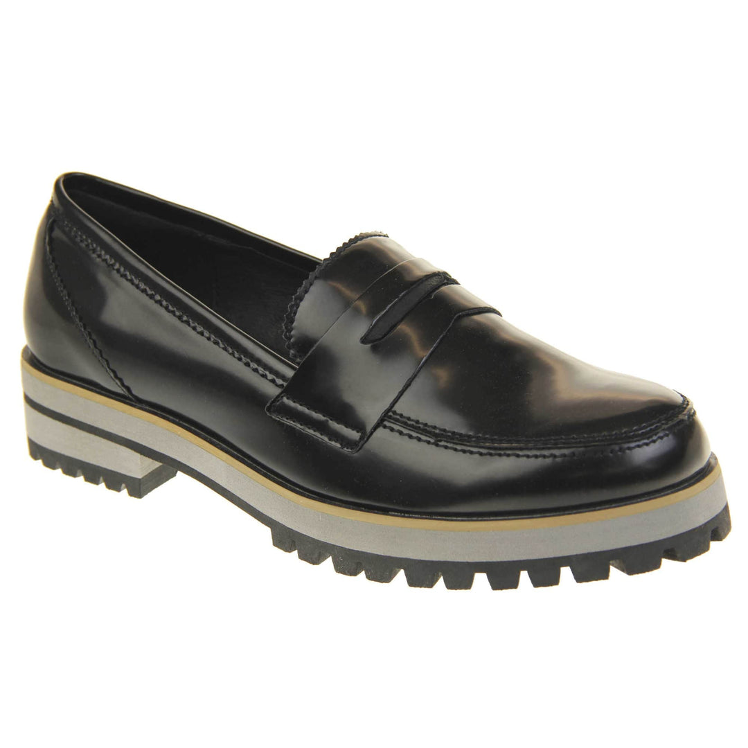 Loafer chunky sole. Loafer style shoes with a black faux leather upper. With a bar detail over the foot. Chunky black and grey sole with slip resistant grip to the bottom. Right foot at an angle.