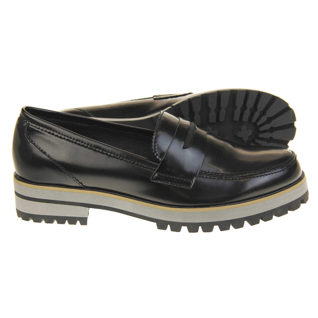 Loafer chunky sole. Loafer style shoes with a black faux leather upper. With a bar detail over the foot. Chunky black and grey sole with slip resistant grip to the bottom. Both feet from a side profile with the left foot on its side behind the the right foot to show the sole.