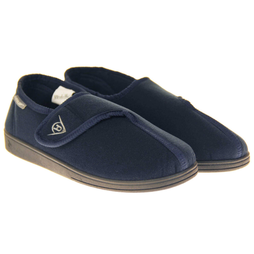 Machine washable slippers. Full back slippers with a navy felt upper. Adjustable touch fasten strap to the top of the foot. Small grey label on the outside rim, with Dunlop branding in white. Navy textile lining. Firm black sole. Both feet together at an angle.