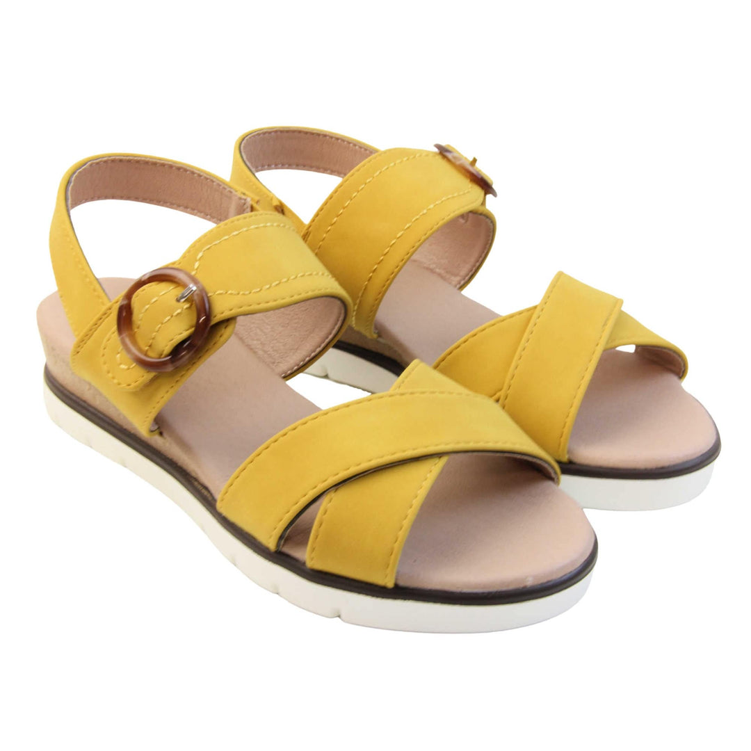 Memory foam sandal. Classic womens strappy sandals with yellow textile straps. Dual toe straps that cross over each other. The ankle strap is touch fasten but has a brown buckle detail to look like a buckle fastening. Beige faux leather memory foam insoles. Small wedge heel in cork effect. White outsole with a black rim around the top. Both shoes together from an angle