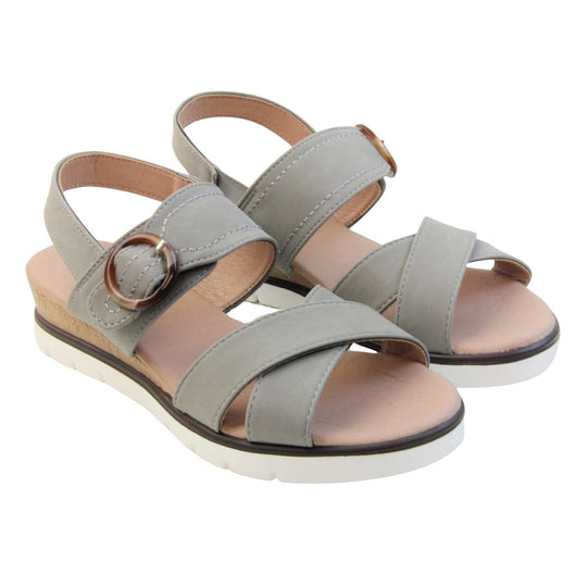 Memory foam wedge sandals. Classic womens strappy sandals with grey textile straps. Dual toe straps that cross over each other. The ankle strap is touch fasten but has a brown buckle detail to look like a buckle fastening. Beige faux leather memory foam insoles. Small wedge heel in cork effect. White outsole with a black rim around the top. Both shoes together from an angle