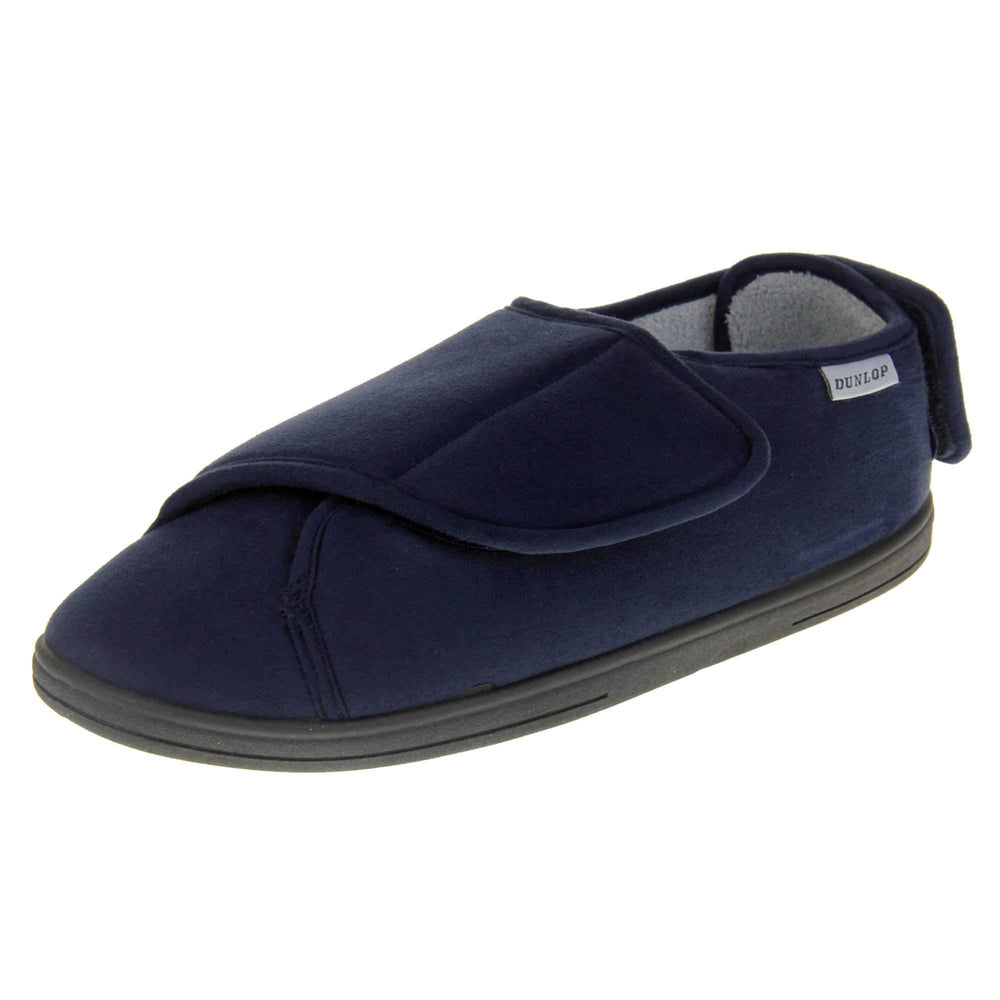 Mens adjustable slippers. Full back slippers with navy blue upper. Adjustable touch fasten strap to the top of the foot and around the back of the heel. Small white label on the outside rim, with Dunlop branding sewn in black. Grey faux fur lining. Left foot at an angle.