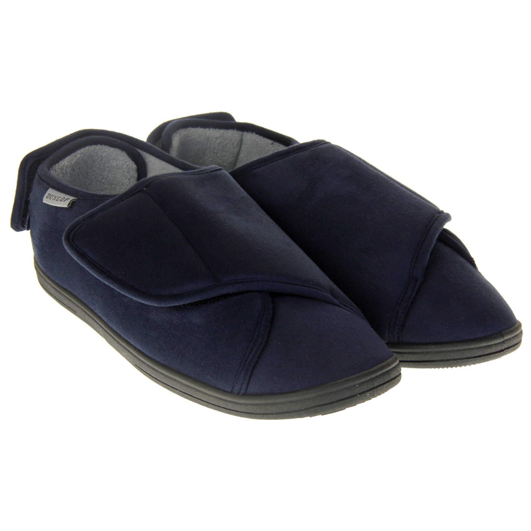 Mens adjustable slippers. Full back slippers with navy blue upper. Adjustable touch fasten strap to the top of the foot and around the back of the heel. Small white label on the outside rim, with Dunlop branding sewn in black. Grey faux fur lining. Both feet together at an angle.