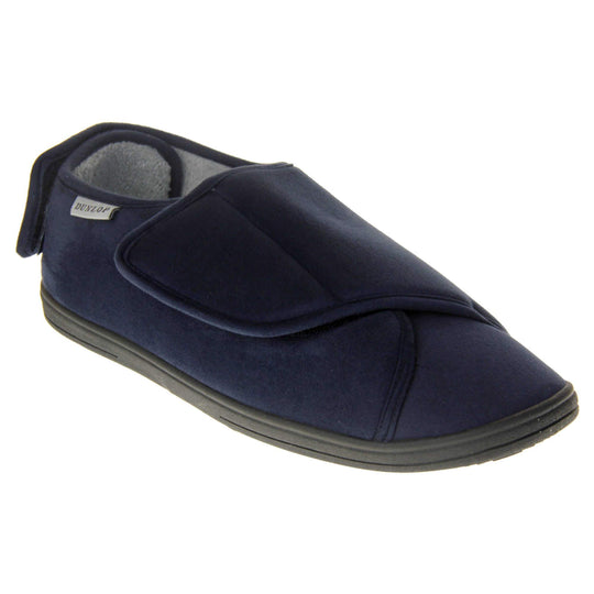 Mens adjustable slippers. Full back slippers with navy blue upper. Adjustable touch fasten strap to the top of the foot and around the back of the heel. Small white label on the outside rim, with Dunlop branding sewn in black. Grey faux fur lining. Right foot at an angle.