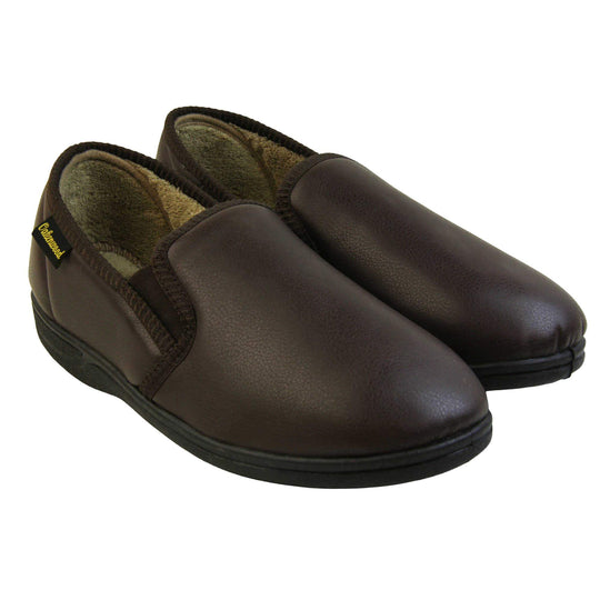 Mens faux leather slippers. Brown faux leather classic full back slipper with beige fleece lining. Both feet together at an angle.
