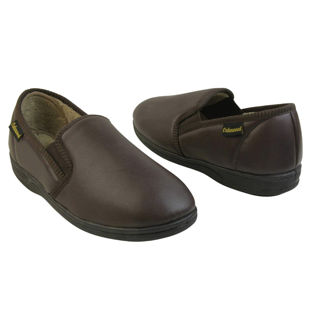 Mens faux leather slippers. Brown faux leather classic full back slipper with beige fleece lining. Both feet facing top to tail at an angle.