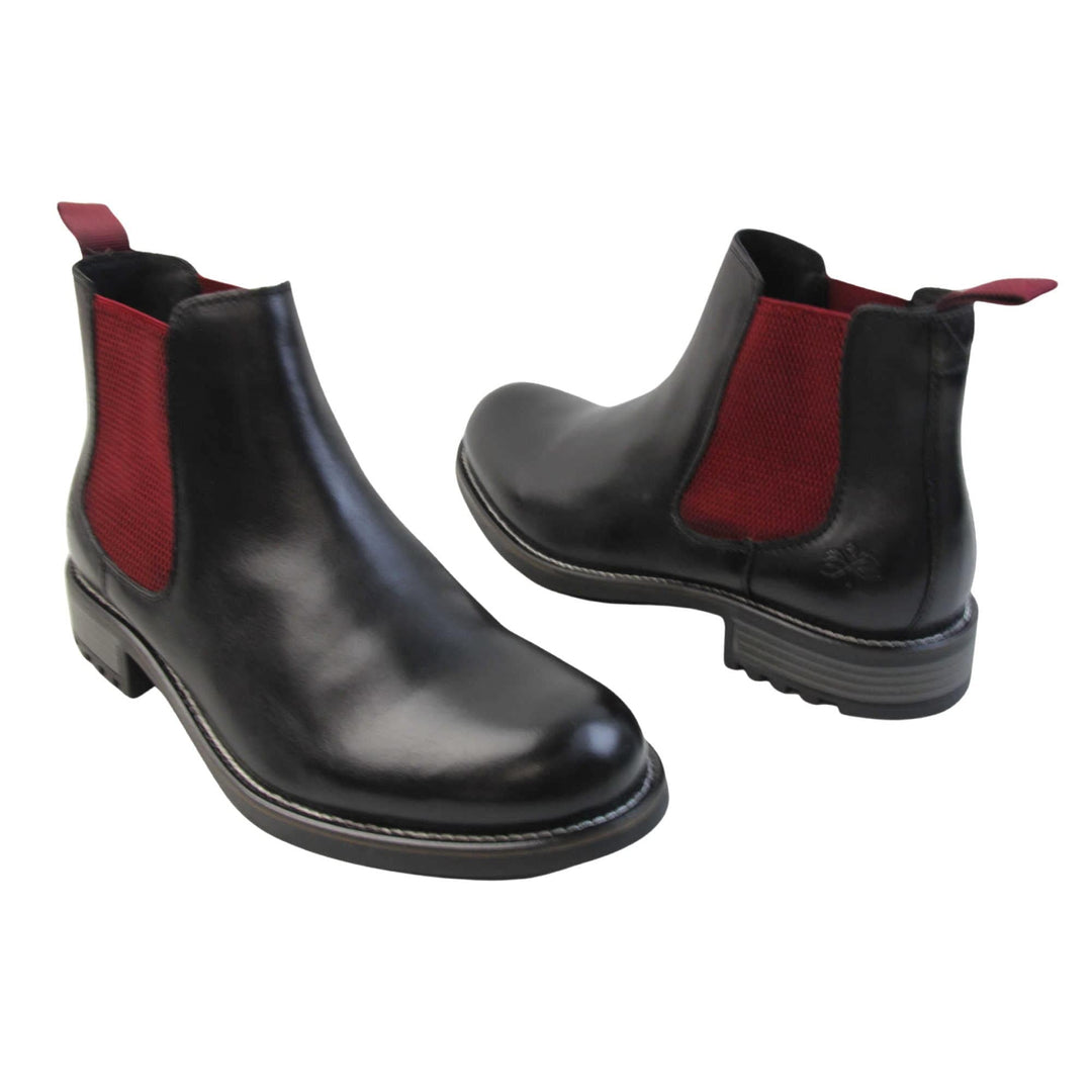 Mens leather Chelsea boots black. Ankle boots with black leather uppers and red textile elasticated side panels. Red textile tab to the back rim to help pull shoes on. Embossed Oakenwood brand to the outside heel of the boot. Black sole with very slight heel. Both feet at an angle facing top to tail.