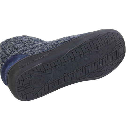 Mens memory foam slippers. Slipper boots with a navy blue knit upper. Navy fabric piping around the collar. Navy textile patch over the heel to reinforce. Thick black synthetic sole with Dunlop branding on. Navy faux fur lining. Close up of bottom of shoe to show the sole.