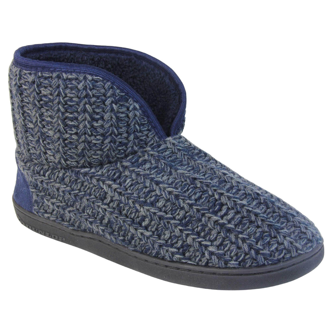 Mens memory foam slippers. Slipper boots with a navy blue knit upper. Navy fabric piping around the collar. Navy textile patch over the heel to reinforce. Thick black synthetic sole with Dunlop branding on. Navy faux fur lining. Right foot at an angle.
