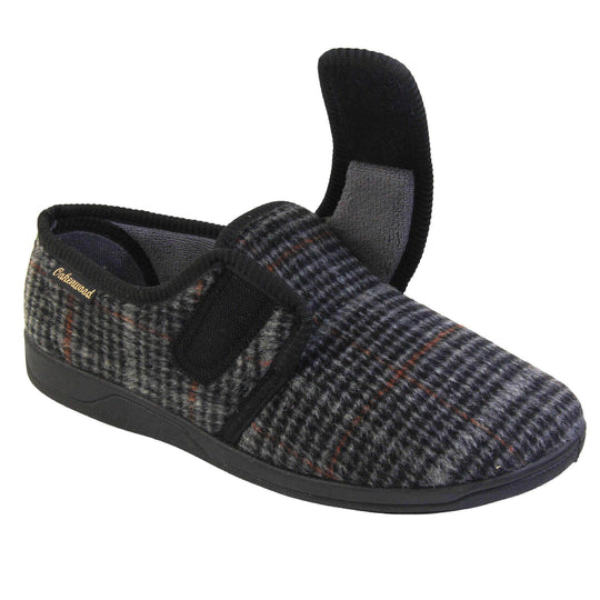 Mens adjustable slippers. Full back slippers with a black and grey check upper and black edging around the strap and collar of the shoe. Touch fasten strap across the bridge of the foot. Chunky black synthetic sole. Right foot at an angle with the strap undone.