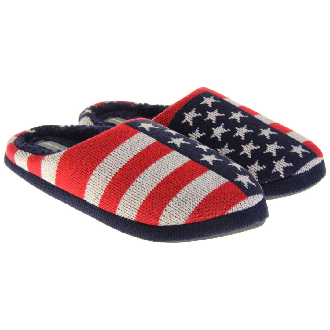 Mens American Flag slippers. Mens slippers in a mule style. With red, white and blue USA flag knit fabric upper. Blue faux fur lining. Black hard synthetic soles with grip to the base. Both feet together from a slight angle.