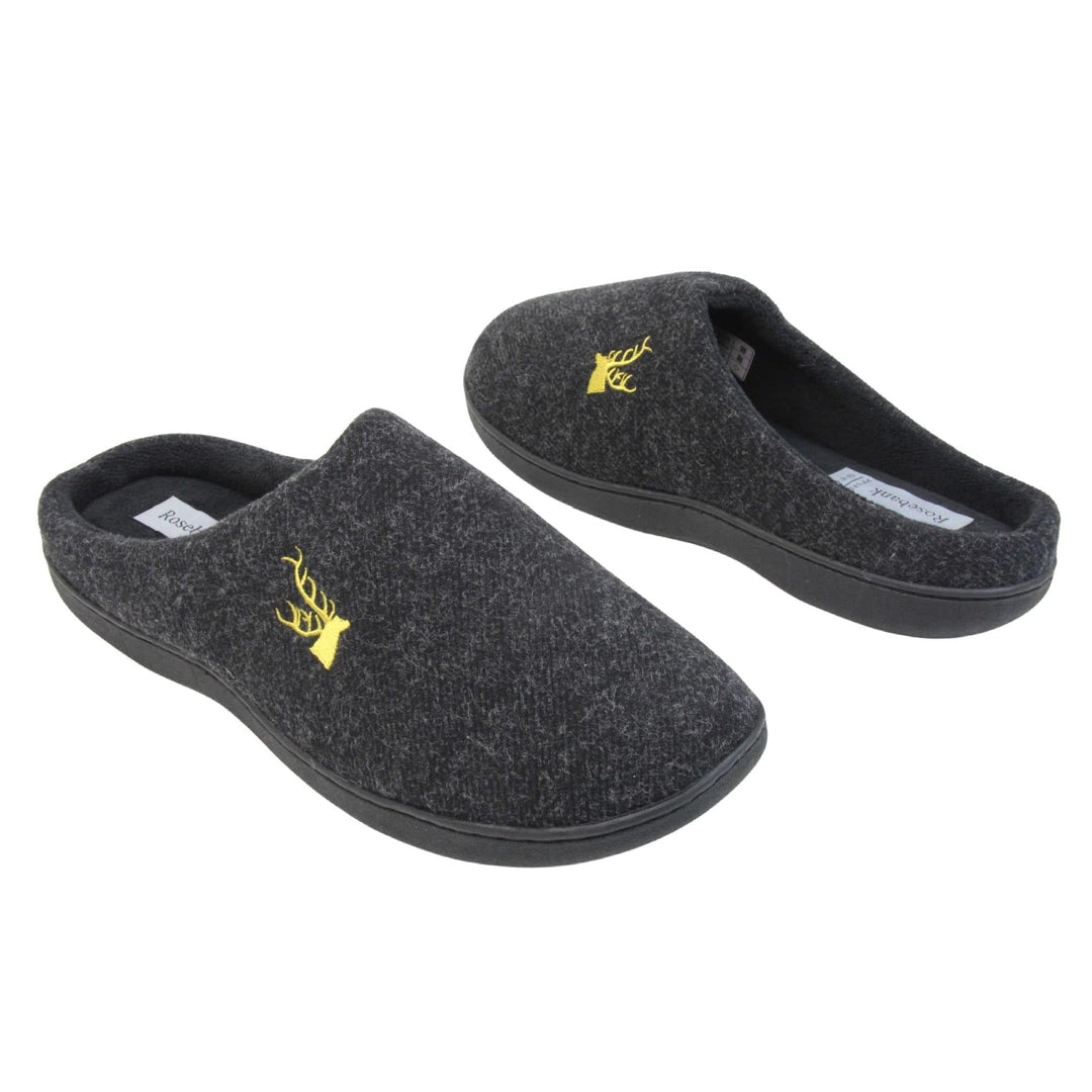 Mens backless slippers. Mule style slippers with black fleece uppers with an embroidered stag head to the top, on the outside. Black terry lining and firm black sole. Both feet at an angle facing top to tail.