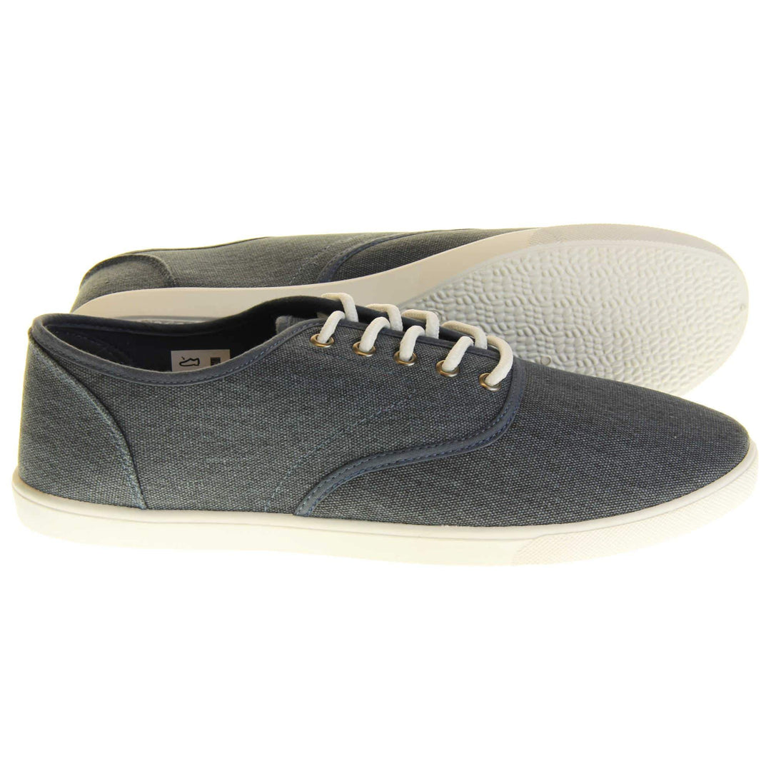 Mens canvas pumps. Navy blue canvas upper with white laces. White synthetic sole and dark textile lining.  Both feet from a side profile with left foot behind the right on its side to show the sole.