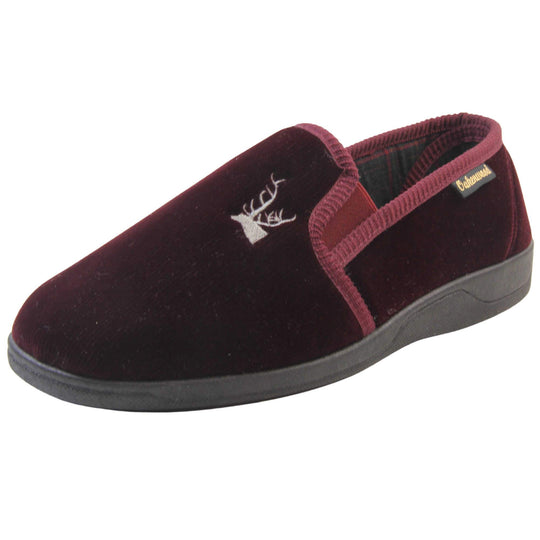 Classic Slippers. Mens full back slippers with a burgundy red velour uppers. Red elasticated panels joining the tongue to the top of the slippers. Grey stag head detail embroidered onto the top of the upper, near the tongue. Small black label on the outside rim, with Oakenwood branding sewn in gold. Plaid textile lining. Left foot at an angle.