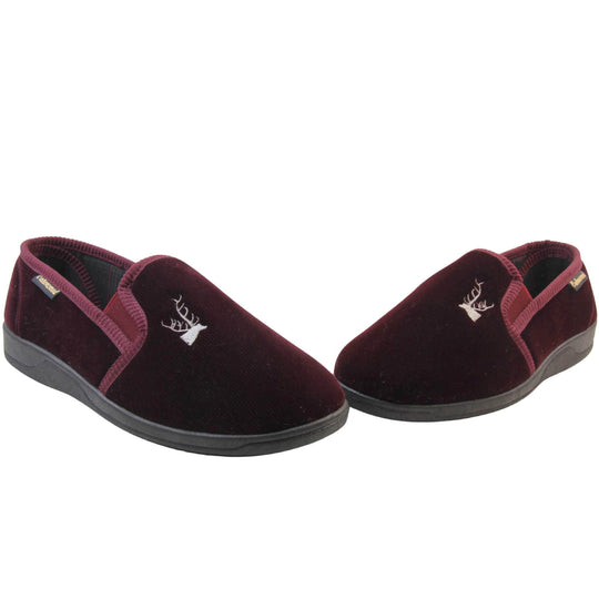 Classic Slippers. Mens full back slippers with a burgundy red velour uppers. Red elasticated panels joining the tongue to the top of the slippers. Grey stag head detail embroidered onto the top of the upper, near the tongue. Small black label on the outside rim, with Oakenwood branding sewn in gold. Plaid textile lining. Both feet in a wide V shape with toes almost touching.