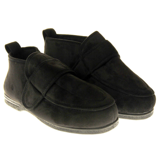 Mens extra wide slippers. Mens orthopaedic slippers in an ankle boot style. With a soft black faux suede upper and black textile lining. With an adjustable touch close top. Thick black outdoor sole. Both feet together at an angle