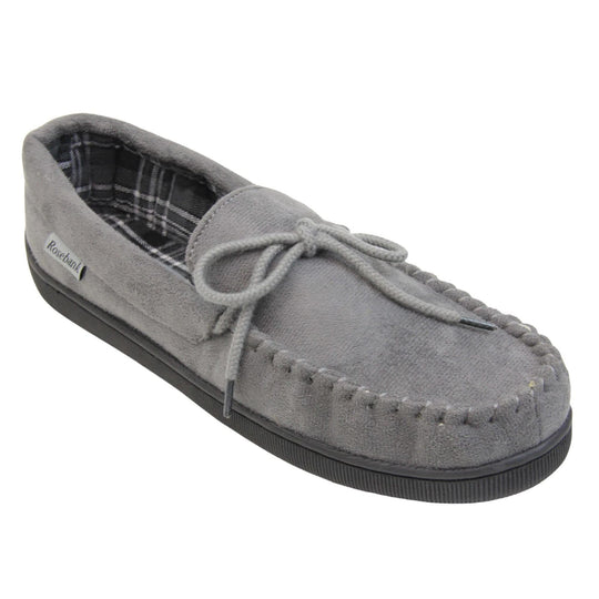 Mens grey moccasin slippers. Moccasin style slipper with grey faux suede upper and rope style bow to the top. Grey Rosebank label to the outside. Dark and light grey and white plaid textile lining. Black rubber sole. Right foot at an angle.