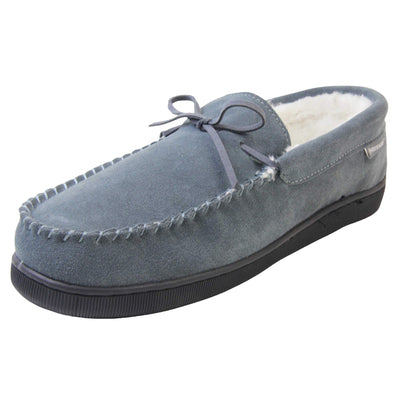 Mens leather moccasin slippers. Closed back slippers in a moccasin style with grey suede leather upper and bow. Cream faux fur lining. Thick black sole. Left foot at an angle.