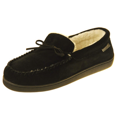 Mens memory foam moccasins. Closed back slippers in a moccasin style with black suede leather upper and bow. Cream faux fur lining. Thick black sole. Left foot at an angle.
