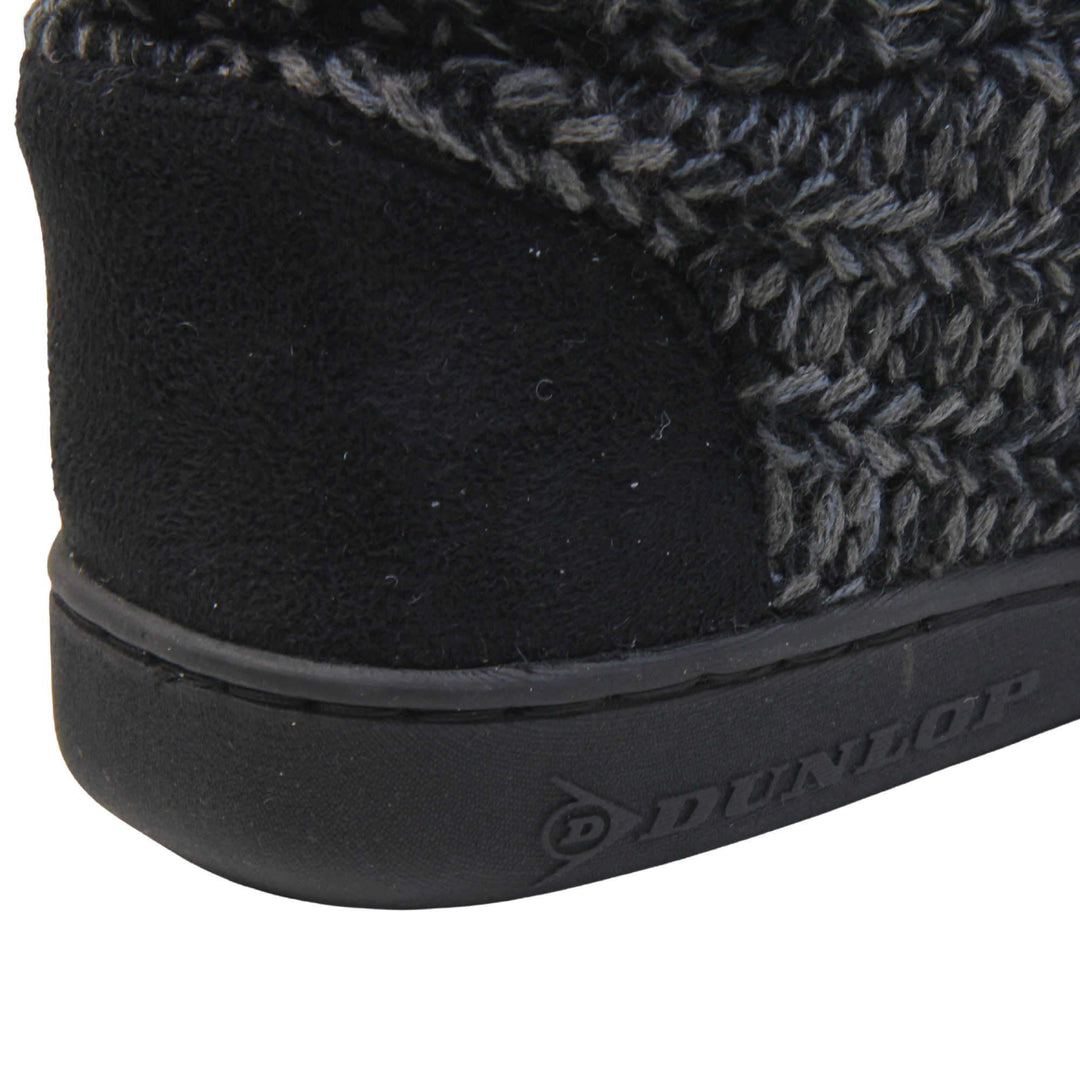 Mens memory foam slipper boots. Slipper boots with a black knit upper. Black fabric piping around the collar. Black textile patch over the heel to reinforce. Thick black synthetic sole with Dunlop branding on. Black faux fur lining. Close up of the heel patch.