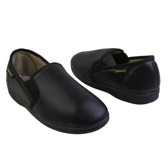 Mens memory foam slippers. Black faux leather classic full back slipper with beige fleece lining. Both feet facing top to tail at an angle.