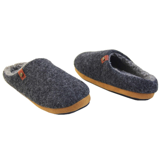 Mens memory foam slippers. Mule style slippers with a black felt upper with brown rim around the base and a brown faux leather strap with stud detail along the collar of the slipper. Grey Wool effect faux fur lining with a grey Dunlop label on the middle of the insole. Firm black sole with wavy lines for grip. Both feet at an angle facing top to tail.
