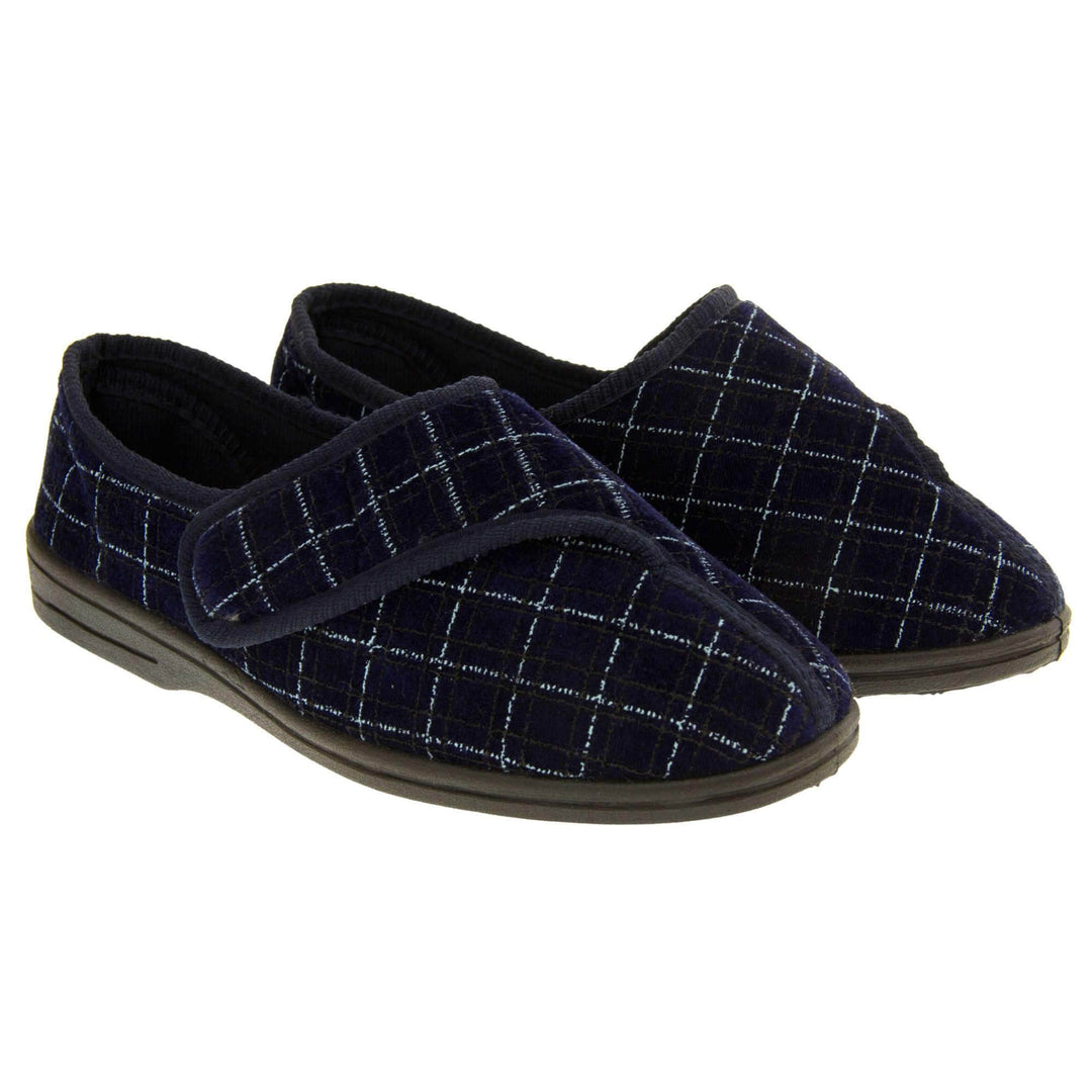 Mens orthopaedic slippers. Full back slippers with a navy and pale blue upper. Touch fasten strap across the bridge of the foot. Chunky black synthetic sole. Navy lining. Both feet together from a slight angle.