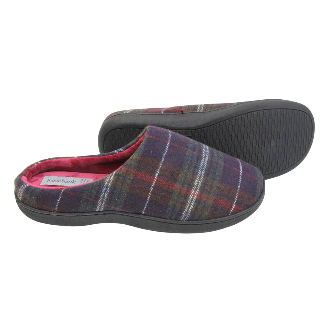 Mule slippers for men. Mule style slippers with fleecy navy and red tartan uppers. Red terry lining and firm black sole. Both feet from a side profile with the left foot on its side behind the the right foot to show the sole.