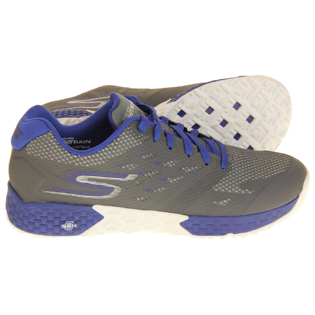 Mens Skechers go train. Grey mesh upper with darker grey overlay. Blue laces and textile lining and small amount of blue detailing. Blue and white Skechers logo to the side of the heel and chunky white and blue outsole with grip.  Both feet from a side profile with the left foot on its side to show the sole.