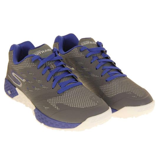 Mens Skechers go train. Grey mesh upper with darker grey overlay. Blue laces and textile lining and small amount of blue detailing. Blue and white Skechers logo to the side of the heel and chunky white and blue outsole with grip. Both shoes together at an angle.