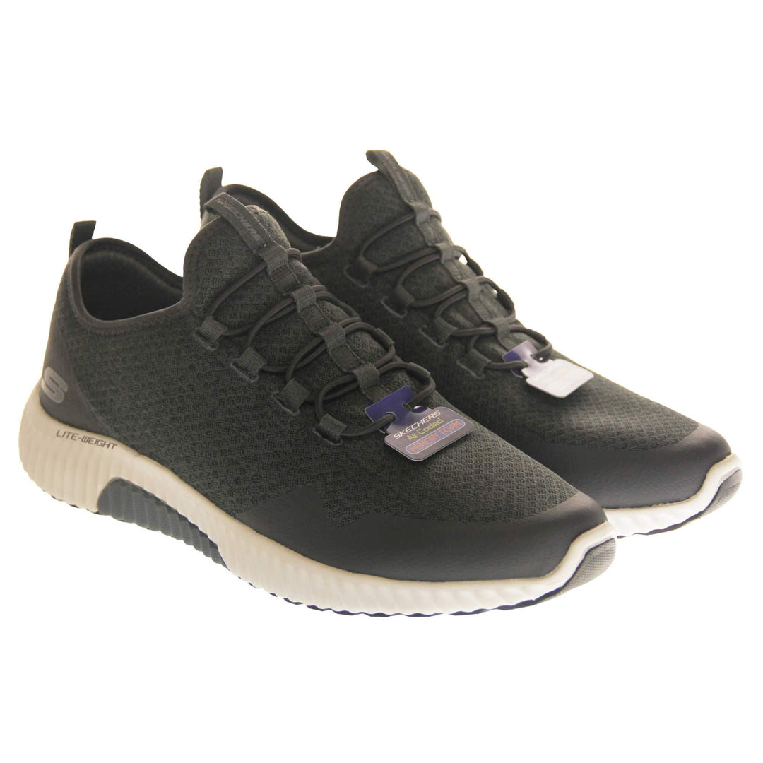 Mens slip on Skechers. Charcoal grey mesh upper with black elasticated laces for a slip on trainer. Black Skechers logo to the heel and chunky white outsole with black bottom with grip. Both shoes together at an angle.