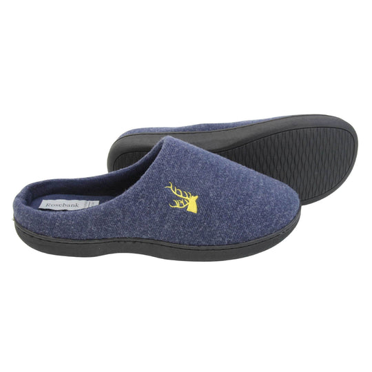 Mens slip on slippers. Mule style slippers with blue fleece uppers with an embroidered stag head to the top, on the outside. Blue terry lining and firm black sole. Both feet from a side profile with the left foot on its side behind the the right foot to show the sole.